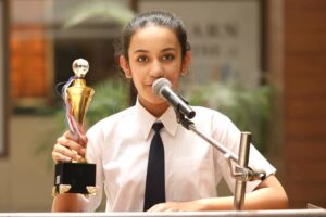 Schoolgirl raising trophy and giving speech at awards ceremony
